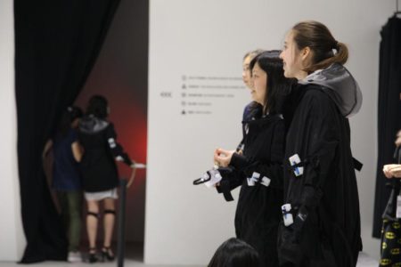 Visitors wearing a garment with Vibropixels attached view themselves in a mirror.