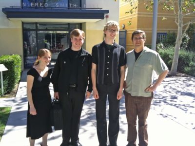 A portait of four musicians in front of a concert hall.